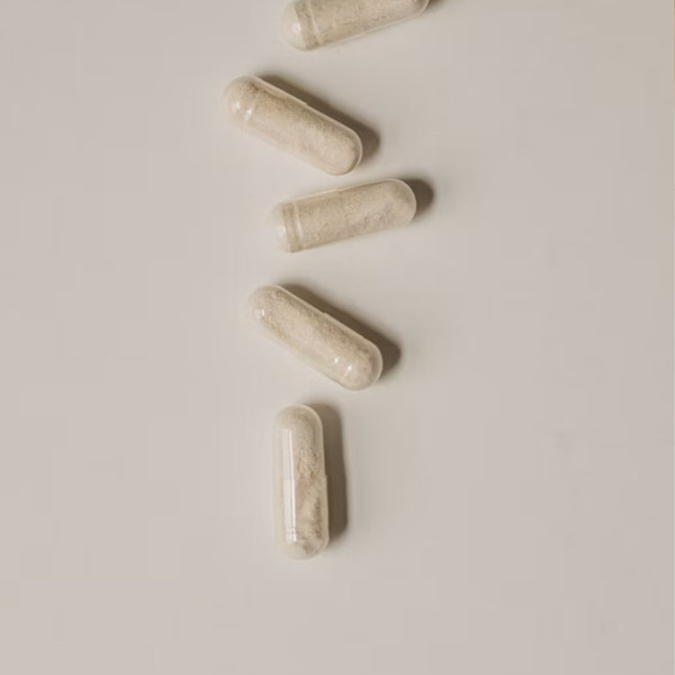 Four off-white L-Theanine capsules arranged diagonally on a plain light gray background.