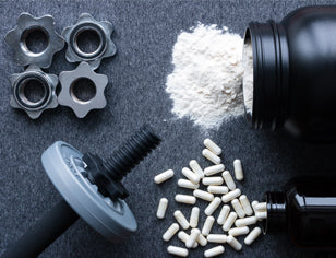 white protein powder and capsules spilling out of bottles with weights on black background