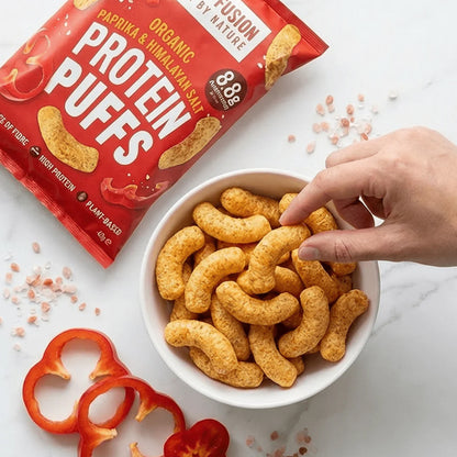 Protein puffs in a bowl with a hand reaching for one, next to a package of Protein Puffs.