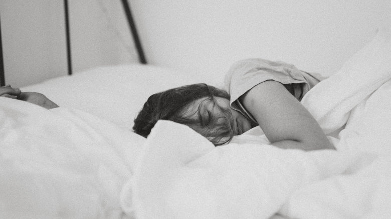 Black and white picture of woman asleep in white sheets