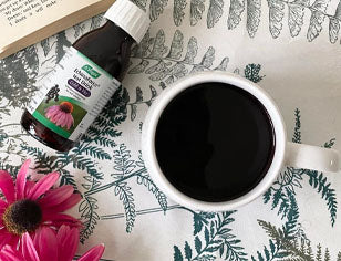 Cup of coffee with a bottle of a. vogel and pink flower on a patterned surface