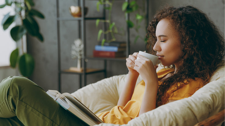 woman sitting in comfortable chair holding calming drink
