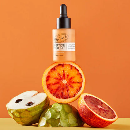 Peptide serum bottle with blood oranges and a green fruit on an orange background