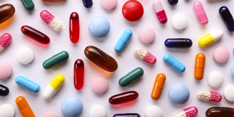 colourful capsules and tablets on a pink background