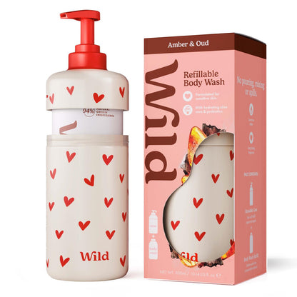 A refillable Wild Amber &amp; Oud Refill Body Wash bottle with a red pump and red heart pattern next to its pink retail box labeled Wild Amber &amp; Oud.