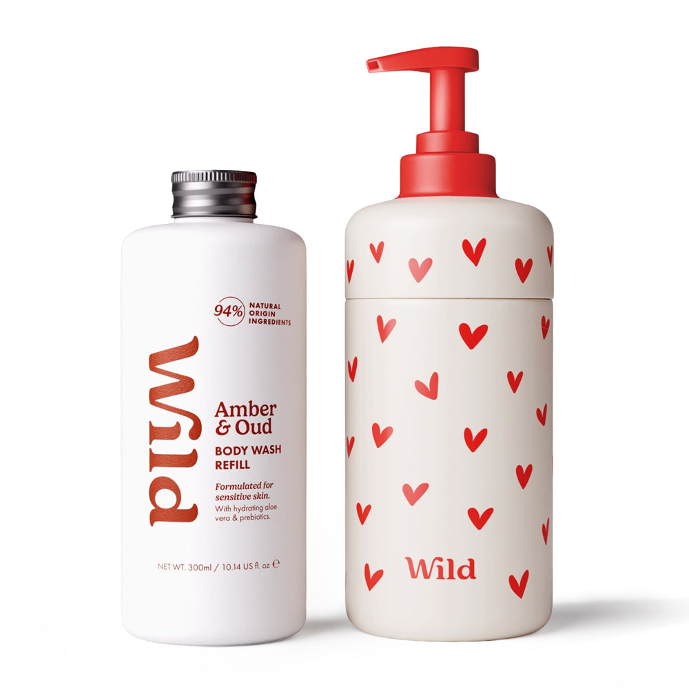 Wild Amber &amp; Oud body wash refill set featuring a 300ml white bottle with a silver cap and a matching white pump bottle decorated with red hearts, both on a white background.