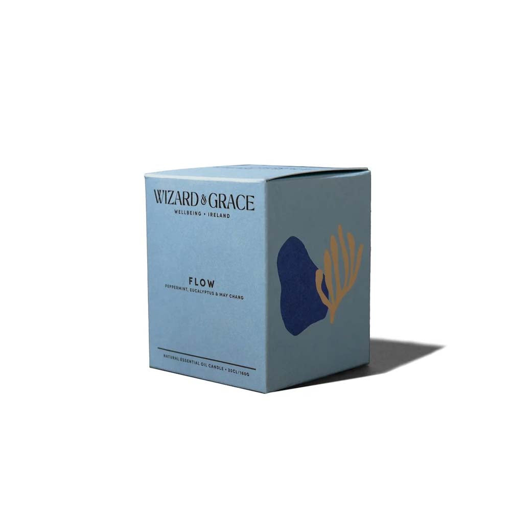 Light blue packaging box for the Wizard &amp; Grace "FLOW" natural essential oil candle, featuring dark blue and gold abstract botanical graphics on a plain white background.
