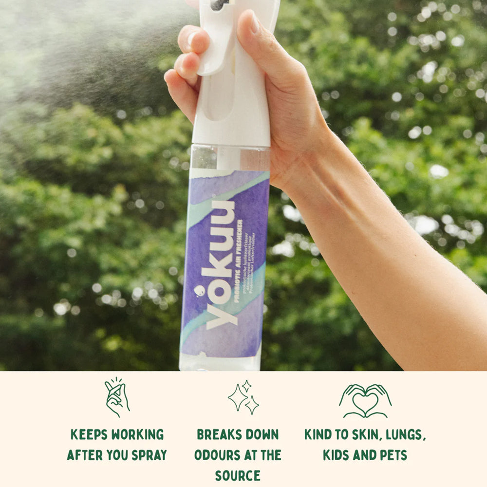 Hand holding a Yokuu spray bottle with greenery in the background